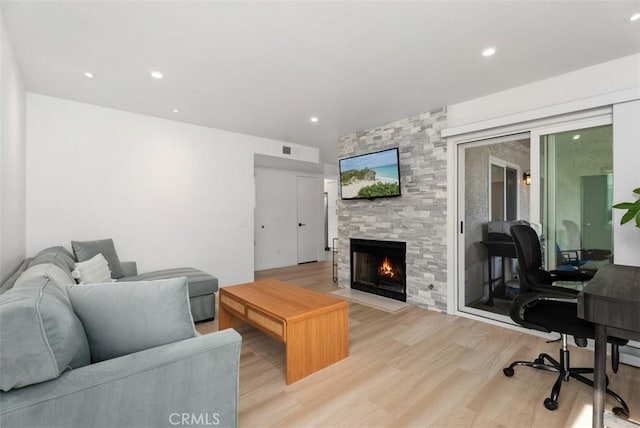 living room with light wood-type flooring and a stone fireplace