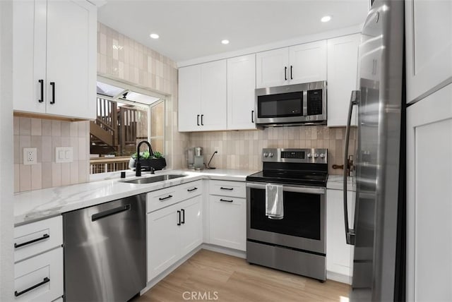 kitchen featuring appliances with stainless steel finishes, light hardwood / wood-style floors, white cabinetry, and sink