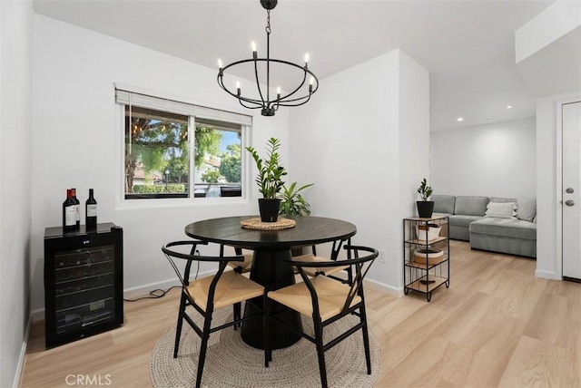 dining area featuring an inviting chandelier, beverage cooler, and light hardwood / wood-style flooring