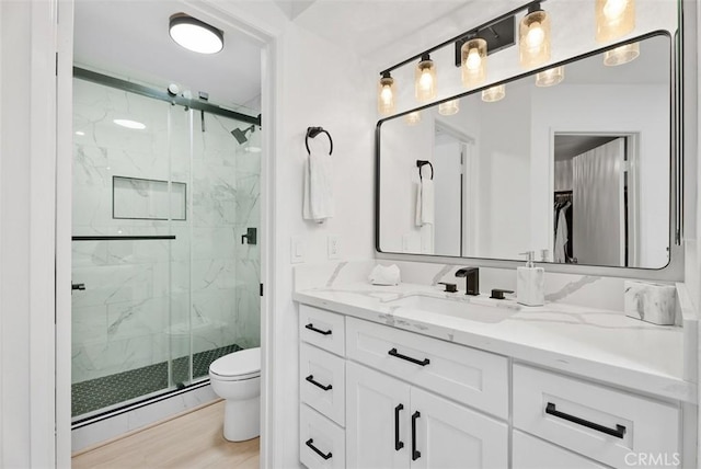 bathroom with vanity, toilet, baseboard heating, an enclosed shower, and wood-type flooring