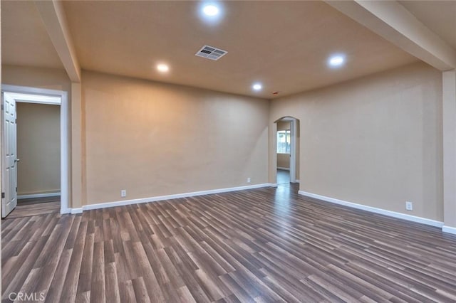 spare room featuring beamed ceiling and dark hardwood / wood-style floors