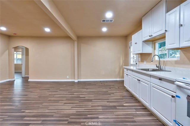 kitchen with white range oven, white cabinetry, sink, and hardwood / wood-style flooring