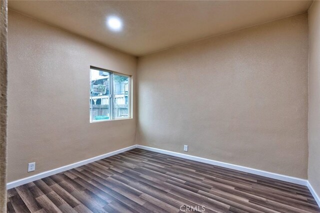 unfurnished room with dark wood-type flooring