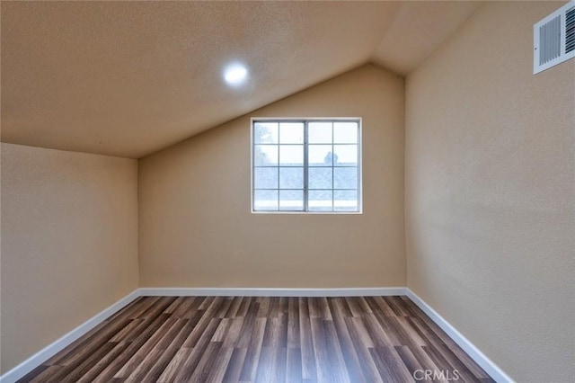 bonus room with a textured ceiling, lofted ceiling, and dark wood-type flooring