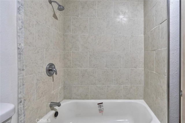 bathroom with tiled shower / bath combo and toilet