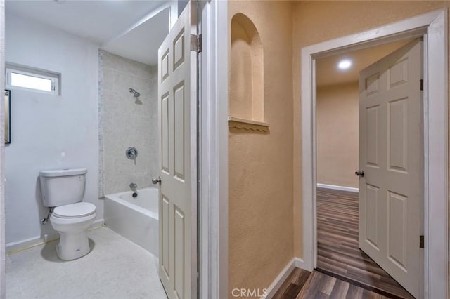 bathroom with hardwood / wood-style floors, tiled shower / bath combo, and toilet