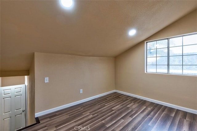 bonus room with a textured ceiling, dark hardwood / wood-style flooring, and vaulted ceiling