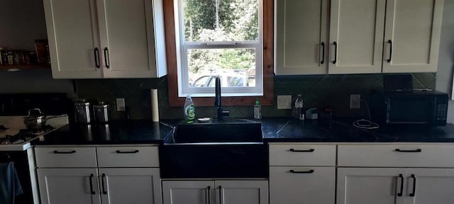 kitchen featuring white cabinetry, white range with gas stovetop, tasteful backsplash, and sink