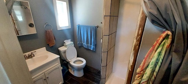 bathroom featuring toilet, vanity, and walk in shower