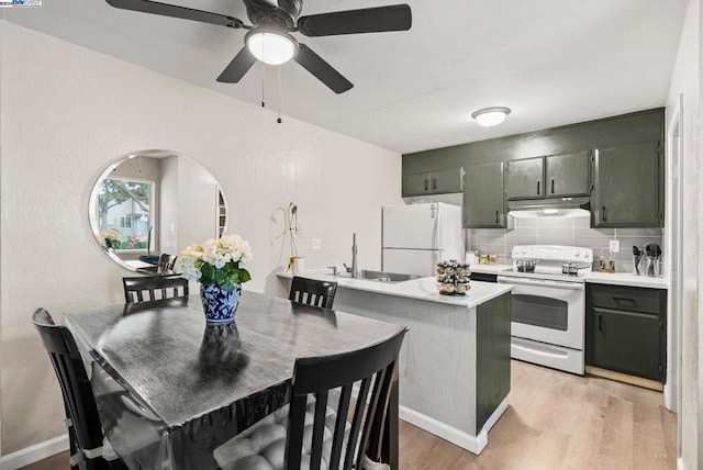 kitchen with white appliances, sink, decorative backsplash, light wood-type flooring, and a breakfast bar area