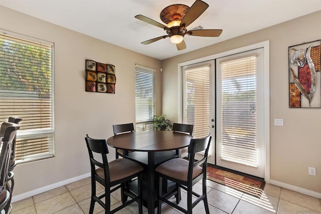 tiled dining space with ceiling fan and a healthy amount of sunlight