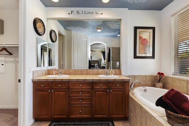 bathroom with vanity and tiled tub