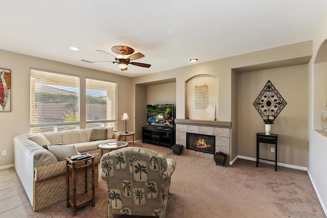 carpeted living room with ceiling fan and a tiled fireplace