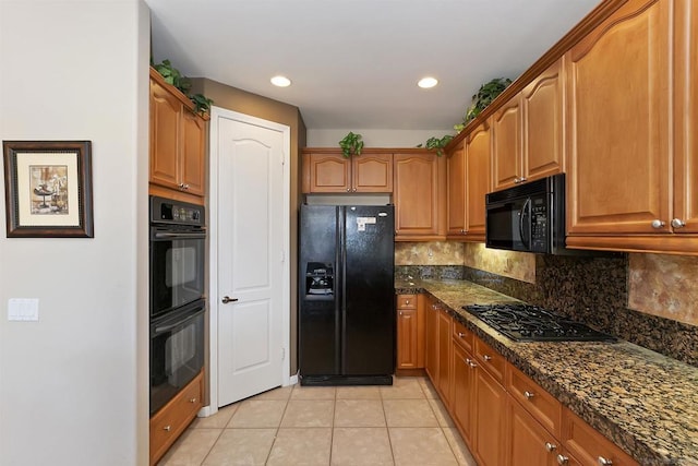 kitchen with light tile patterned floors, tasteful backsplash, dark stone counters, and black appliances