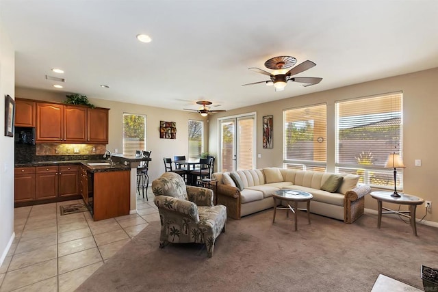 tiled living room with ceiling fan and sink