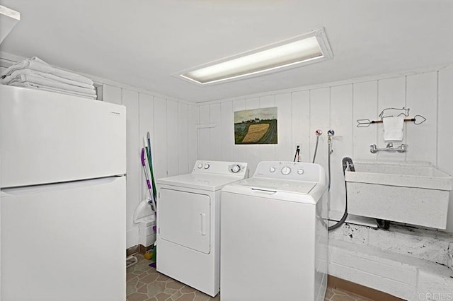 laundry room featuring washer / clothes dryer, wooden walls, and sink