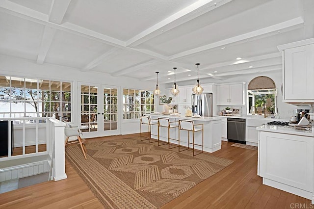 kitchen with white cabinetry, a center island, stainless steel appliances, and light hardwood / wood-style floors