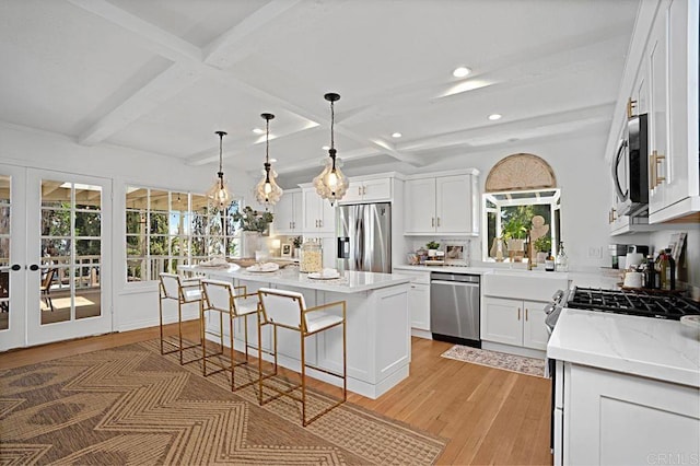 kitchen featuring beamed ceiling, a center island, white cabinetry, and appliances with stainless steel finishes