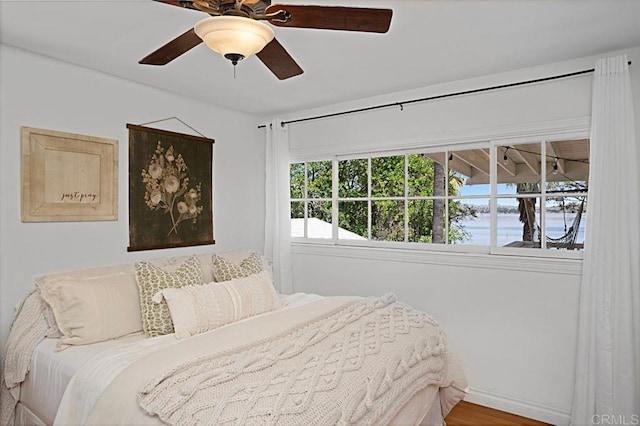 bedroom featuring ceiling fan, a water view, and hardwood / wood-style flooring