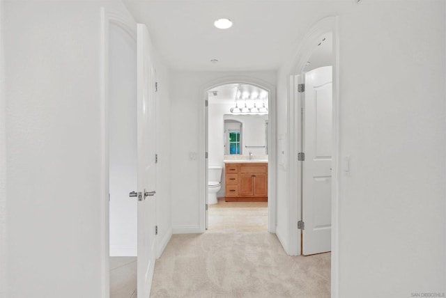 hall featuring sink and light colored carpet