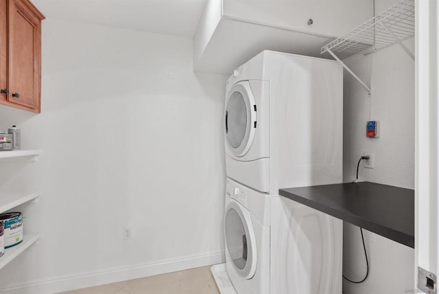 washroom with cabinets and stacked washer and clothes dryer