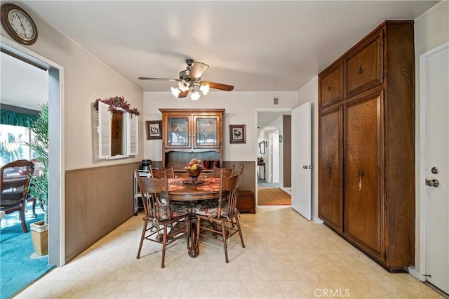 dining room with a wealth of natural light, wooden walls, and ceiling fan