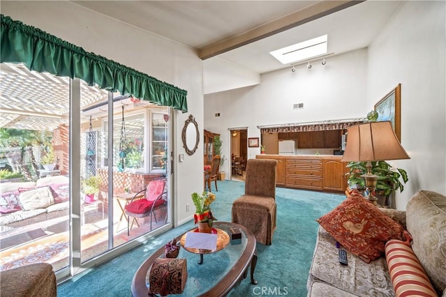 carpeted living room with beamed ceiling, a wealth of natural light, and a skylight