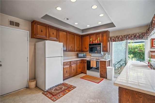 kitchen with white appliances, a raised ceiling, and sink