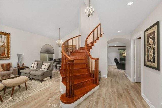 stairs featuring wood-type flooring and an inviting chandelier