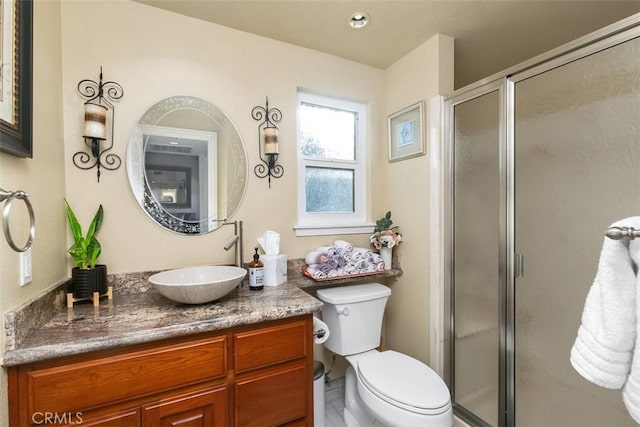 bathroom with vanity, a shower with door, and toilet