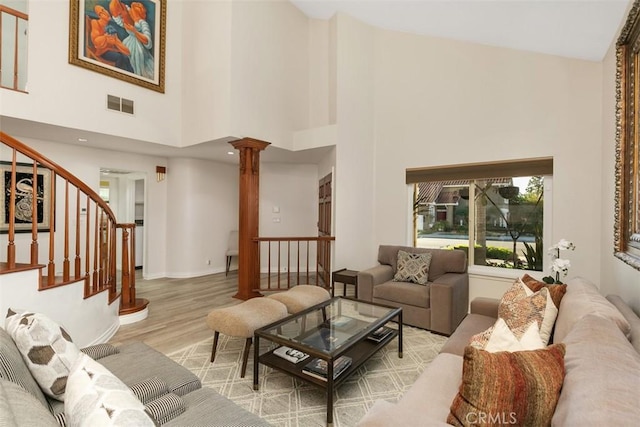 living room with light wood-type flooring, a high ceiling, and ornate columns