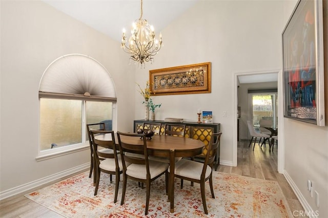 dining area with light hardwood / wood-style flooring, vaulted ceiling, and an inviting chandelier