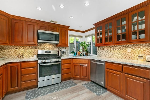 kitchen with sink, tasteful backsplash, light stone countertops, and stainless steel appliances