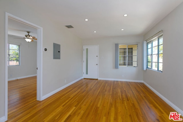 spare room featuring electric panel, ceiling fan, and wood-type flooring