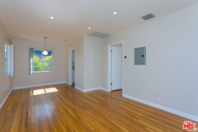 unfurnished room featuring electric panel and light hardwood / wood-style flooring