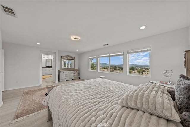 bedroom featuring light hardwood / wood-style floors and ensuite bath