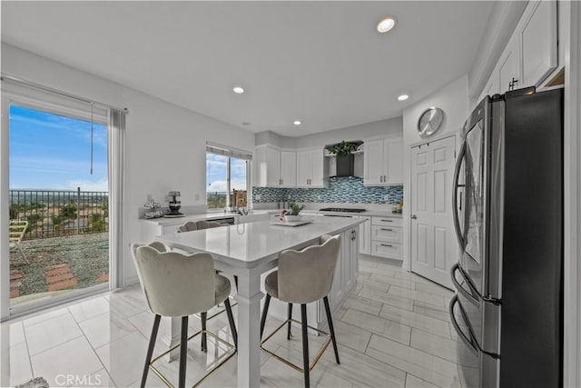 kitchen with white cabinetry, stainless steel fridge, gas cooktop, tasteful backsplash, and a kitchen island