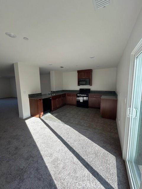 kitchen with black appliances and dark carpet