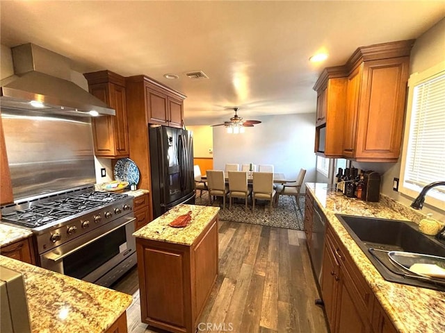 kitchen featuring sink, wall chimney range hood, a center island, and stainless steel appliances