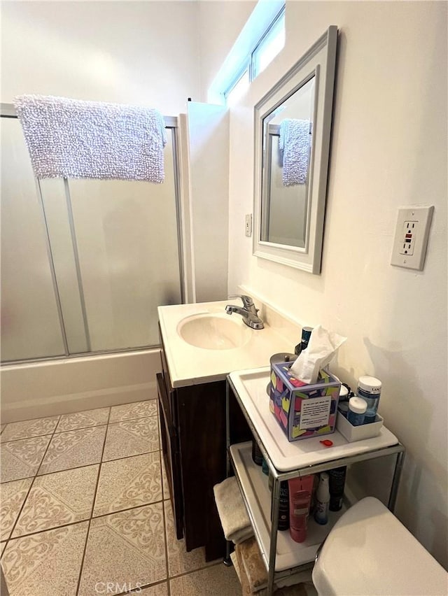 bathroom featuring tile patterned floors, vanity, and enclosed tub / shower combo