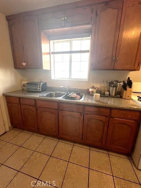 kitchen with light tile patterned floors, stove, and sink