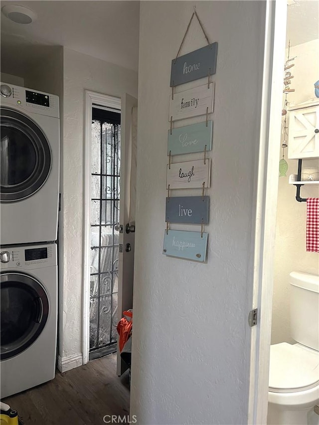 clothes washing area featuring dark hardwood / wood-style flooring and stacked washer and clothes dryer