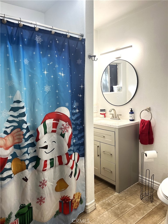 bathroom featuring a shower with curtain, vanity, hardwood / wood-style flooring, and toilet