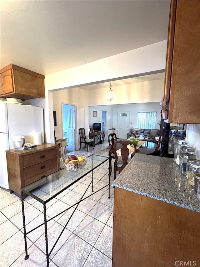 kitchen featuring light tile patterned floors, white refrigerator, and a notable chandelier