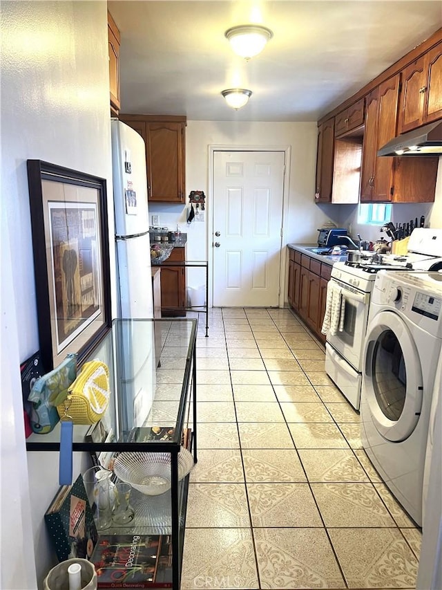 kitchen with sink, washer / dryer, light tile patterned floors, and white gas range oven