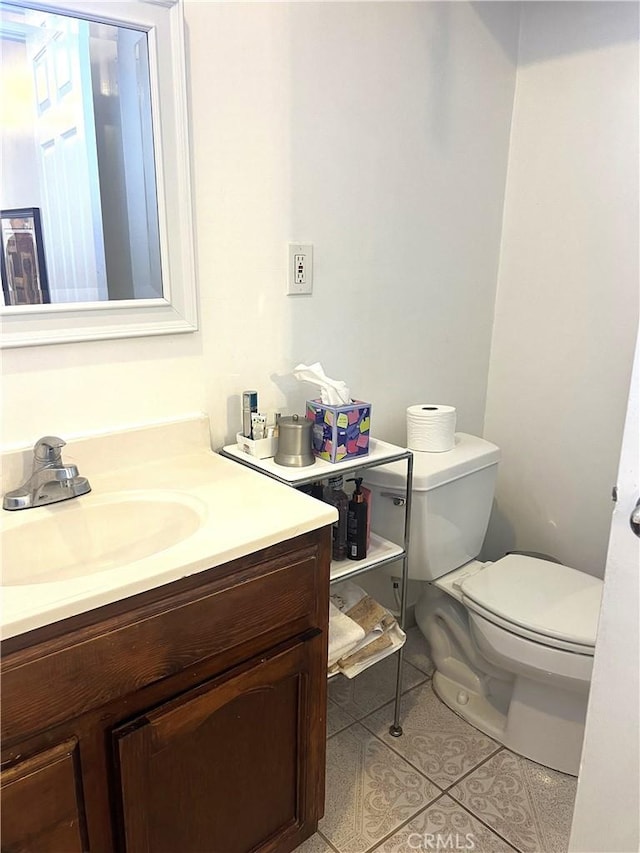 bathroom with toilet, vanity, and tile patterned floors