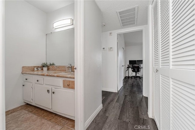 bathroom with hardwood / wood-style flooring, vanity, and a textured ceiling