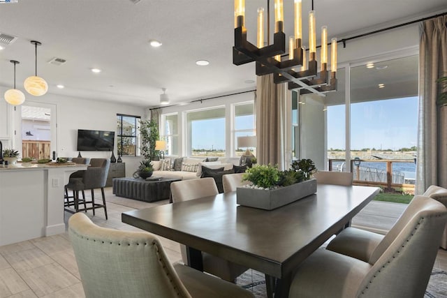 dining space with a water view and a notable chandelier