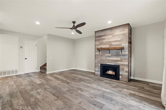 unfurnished living room featuring hardwood / wood-style flooring, ceiling fan, and a tile fireplace