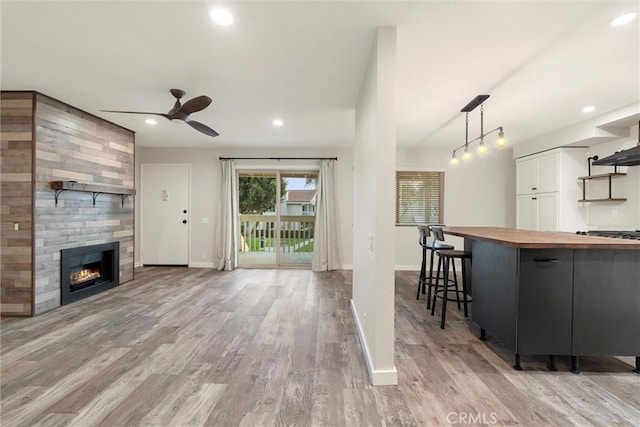 7422 Seastar Unit 8, Huntington Beach, CA 92648 - kitchen featuring wooden counters, open shelves, ceiling fan, light wood finished floors, and a large fireplace